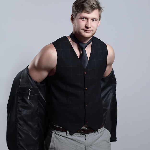 Young businessman in a business suit without a shirt holds a jacket over his shoulder