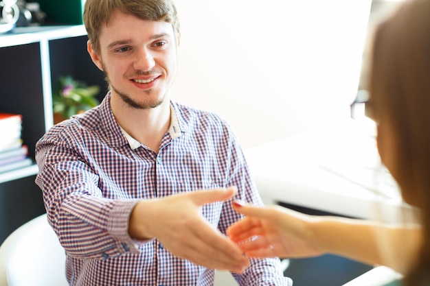 Young businessman and businesswoman shaking hands in office