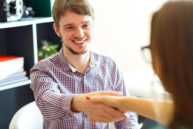 Young businessman and businesswoman shaking hands in office