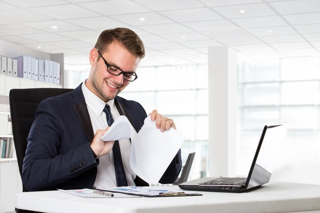 Young businessman checking paper beside in front of laptop