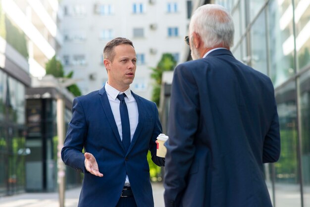 Young businessman discussing something positive with his mature colleague