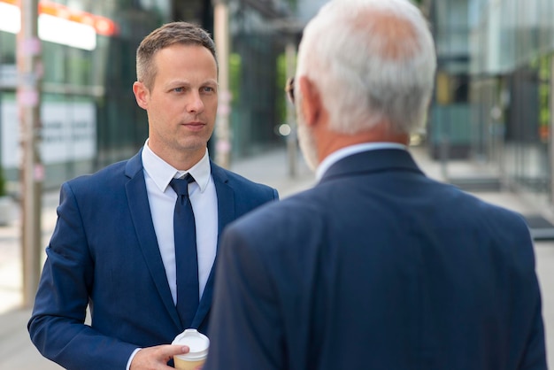 Young businessman discussing something positive with his mature colleague