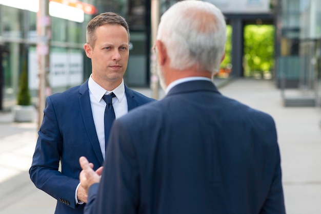 Young businessman discussing something positive with his mature colleague