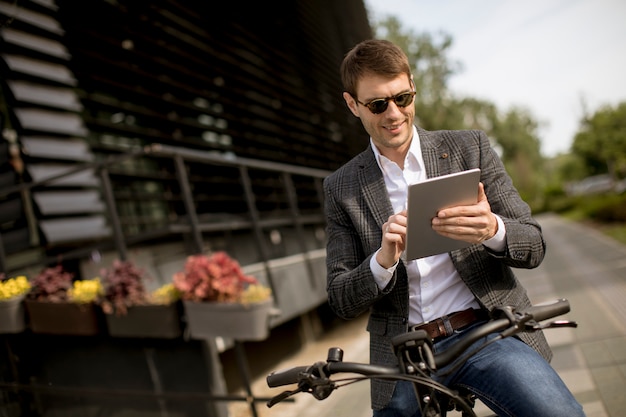 Young businessman on the ebike with digital tablet