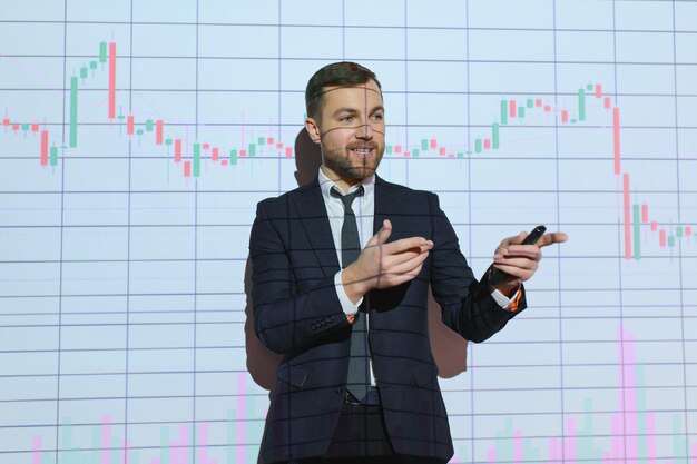 Young Businessman Explaining Graphs To His Colleagues On Projector