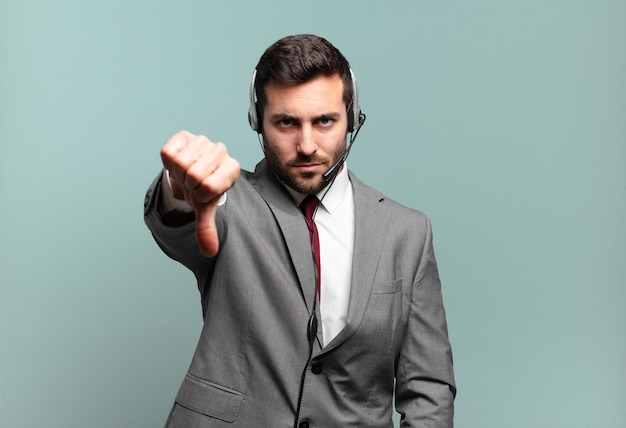 Young businessman feeling cross, angry, annoyed, disappointed or displeased, showing thumbs down with a serious look telemarketing concept