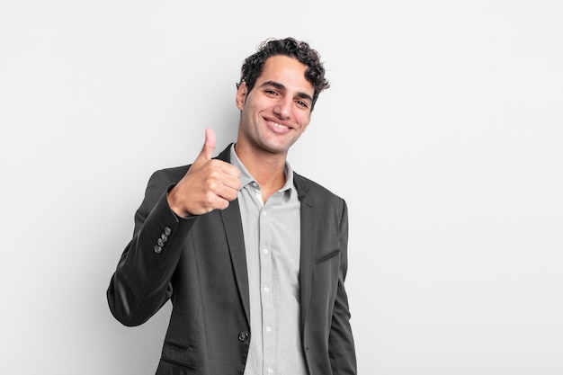 Молодой бизнесмен чувствует себя гордым, беззаботным, уверенным и счастливым, позитивно улыбается и показывает палец вверх