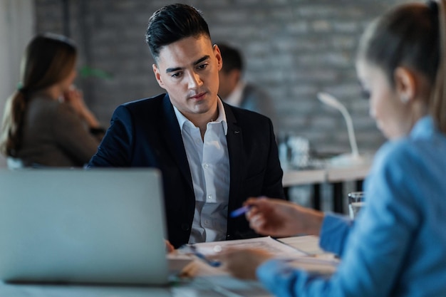 Young businessman feeling worried while reading financial reports with female coworker in the office