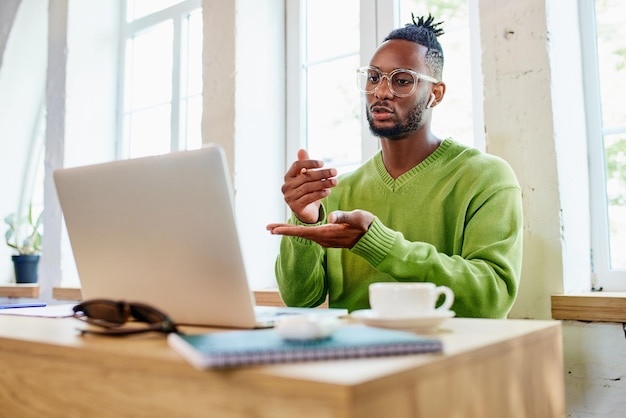 Young businessman freelancer sitting at home and leading online video call via laptop with