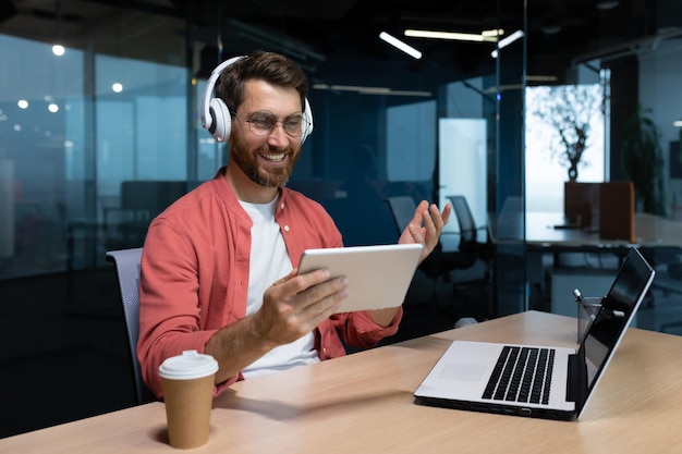 A young businessman freelancer student programmer sits in the office at the table with a laptop in