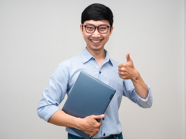 Giovane uomo d'affari sorriso gentile azienda laptop mostra pollice in su isolato