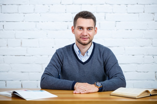 A young businessman guy sits at a table with a book