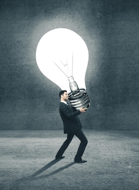 Young businessman holding big lightbulb