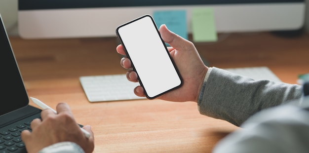 young businessman holding blank screen smartphone while working on his project 