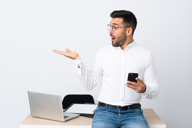 Young businessman holding a mobile phone holding copyspace imaginary on the palm