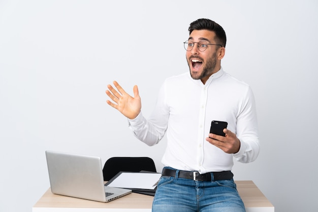 Young businessman holding a mobile phone with surprise facial expression