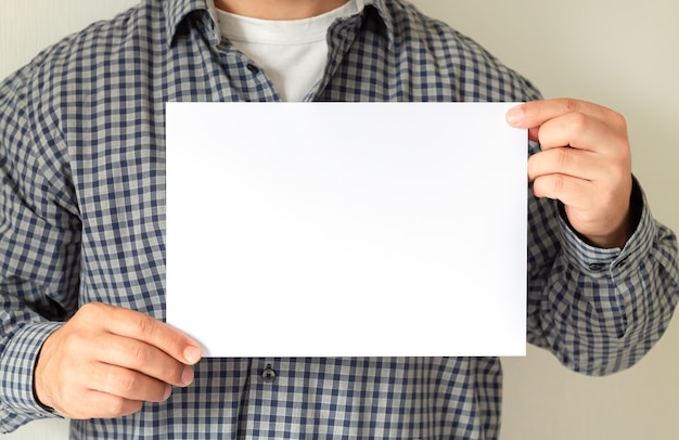 Young businessman holding white blank paper poster or sign