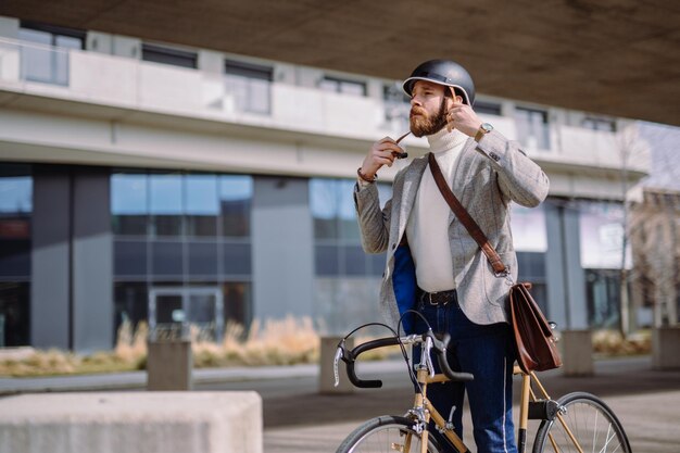 Young businessman is putting on helmet before bicycle rideTravel to work Safety eco transport