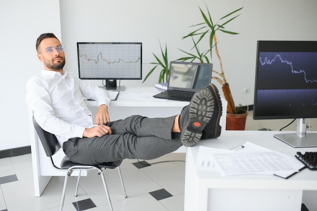 Young businessman is relaxing at workplace and has his feet on desk in office