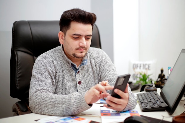 A young businessman is using mobile phone in office.