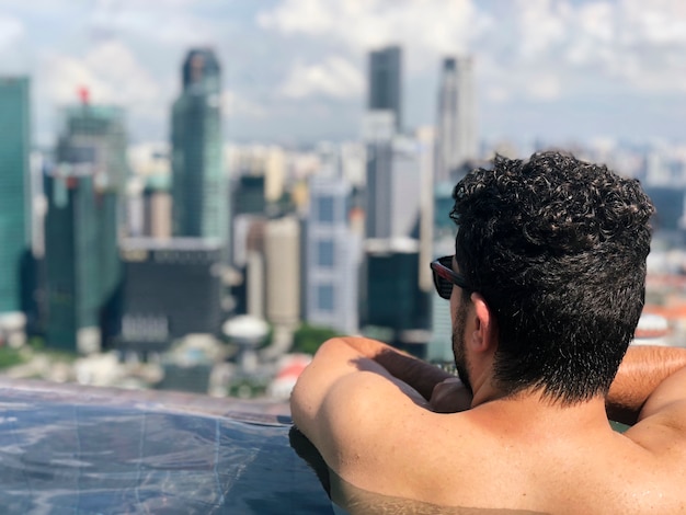 Young businessman looking at Singapore Business District Skyline from an infinity pool