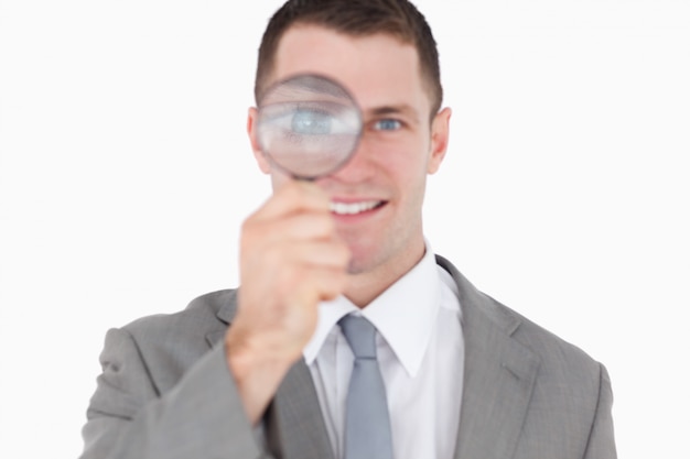 Young businessman looking through a magnifying glass