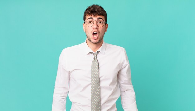 Young businessman looking very shocked or surprised, staring with open mouth saying wow