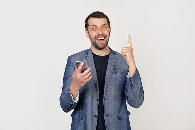 Young businessman man with a beard in a jacket using a smartphone surprised with an idea or question