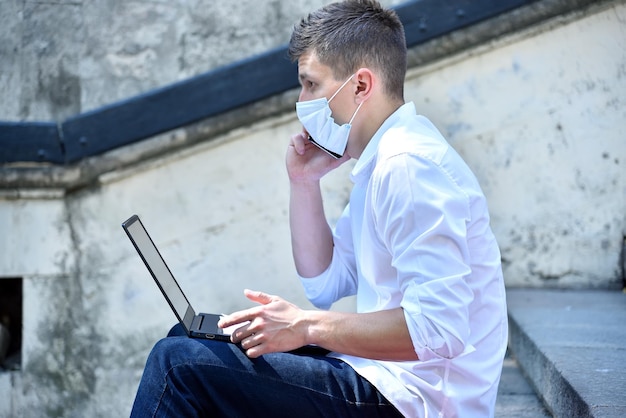 Young businessman in mask working outdoor