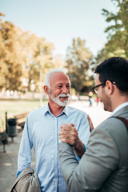 Young businessman meeting with senior colleague outdoors.