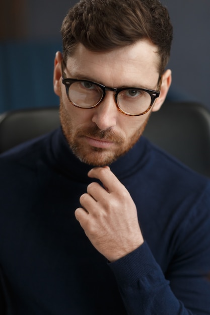 Молодой бизнесмен в офисе бизнес-портрет красивого бородатого мужчины в очках, сидящего на ...