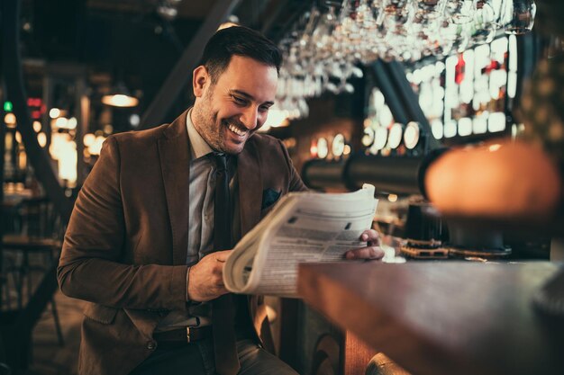 Young businessman reading newspaper at the bar