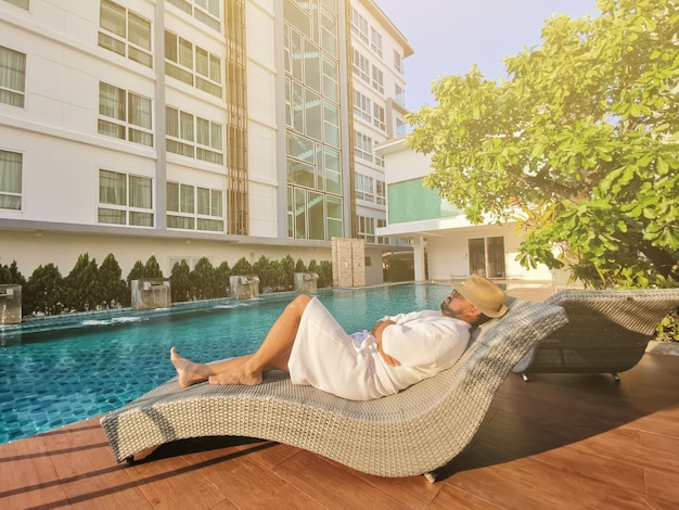 Young businessman relaxing on a deckchair by a swimming pool