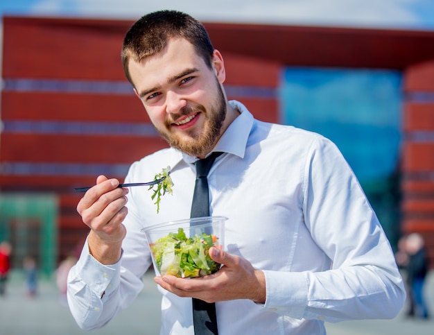 Молодой бизнесмен в рубашке и связи с коробкой для завтрака салата