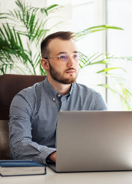 Giovane uomo d'affari in camicia che lavora al suo computer portatile in un ufficio