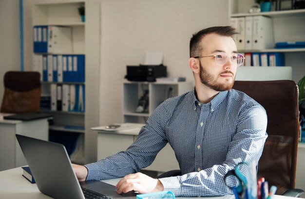 Photo young businessman in shirt working on his laptop in an office