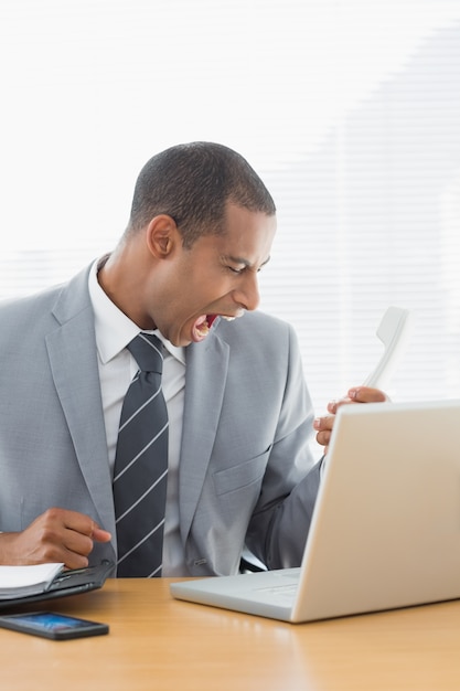 Young businessman shouting into the phone at office