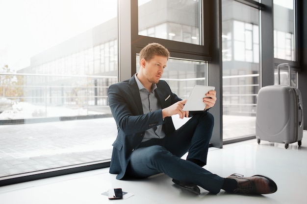 Young businessman sit on floor at window