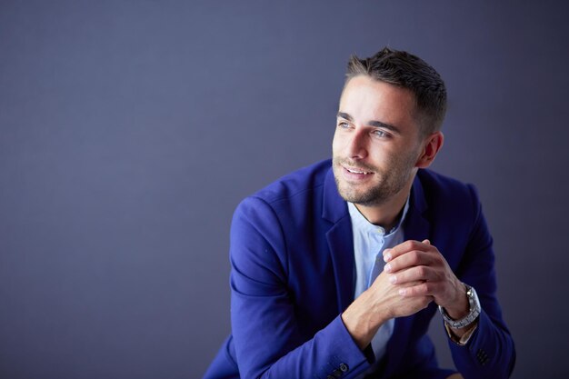 Photo young businessman sitting isolated on grey background