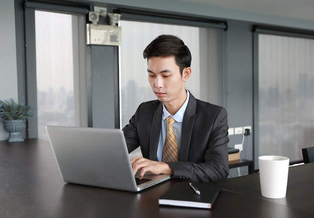 Young businessman sitting at the table on workplace in office using laptop computer