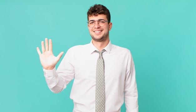 Young businessman smiling and looking friendly, showing number five or fifth with hand forward, counting down