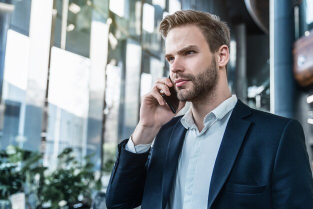 Young businessman standing in office hall and talking on phone