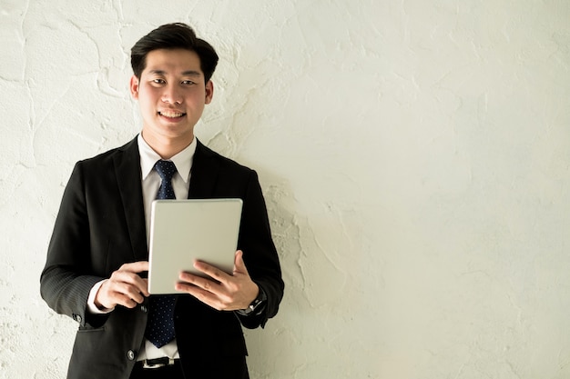 Young businessman standing with tablet near the office window, business concept