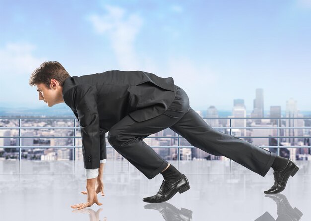 Young businessman in start pose for running on background