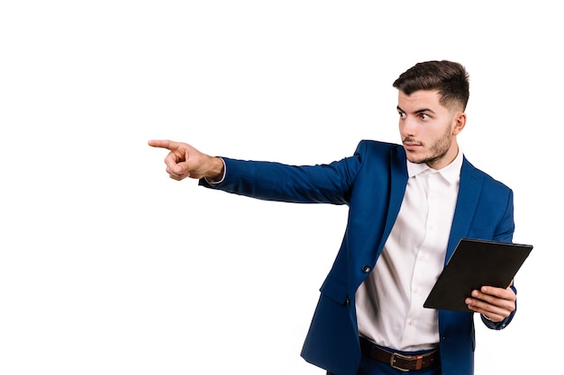 Young businessman in suit pointing seriously while holding tablet