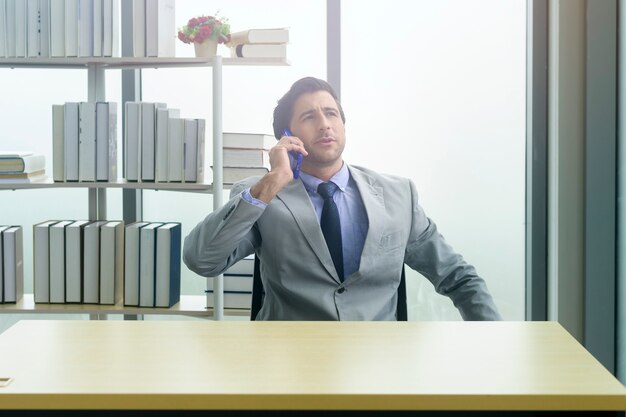 Young businessman in suit using smartphone in modern office