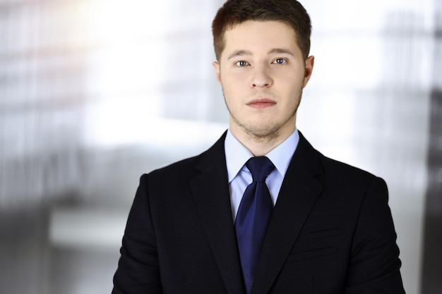 Foto giovane uomo d'affari in giacca e cravatta, mentre si trova in un ufficio soleggiato. concetto di successo aziendale al giorno d'oggi.