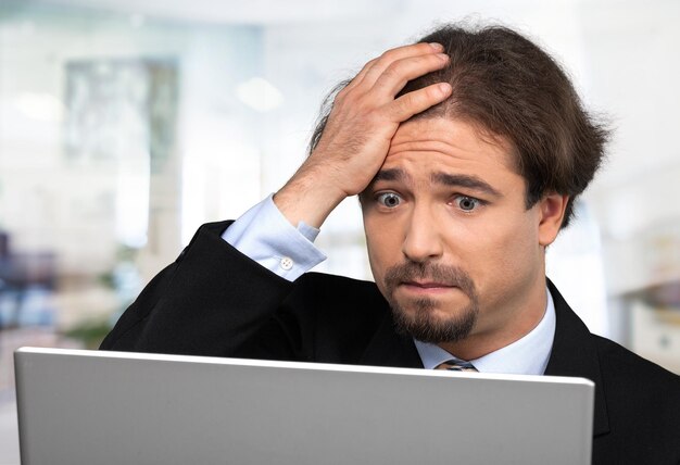 Young businessman in suit with laptop on blurred background