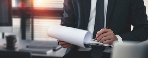 Young businessman in suit writing business papers at desk in modern office