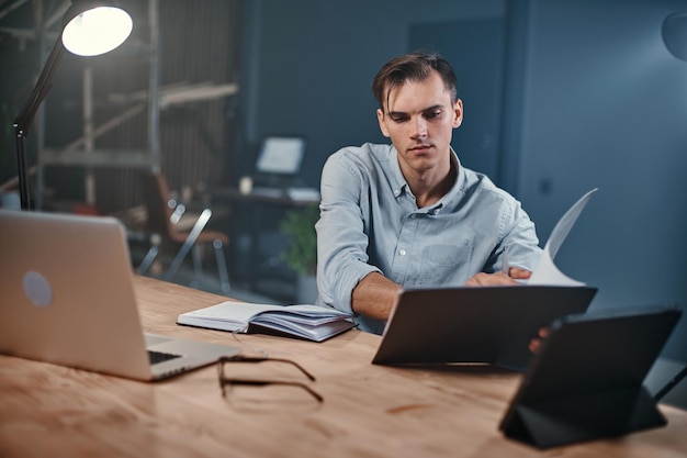 Young businessman taking notes in a notebook in a night office